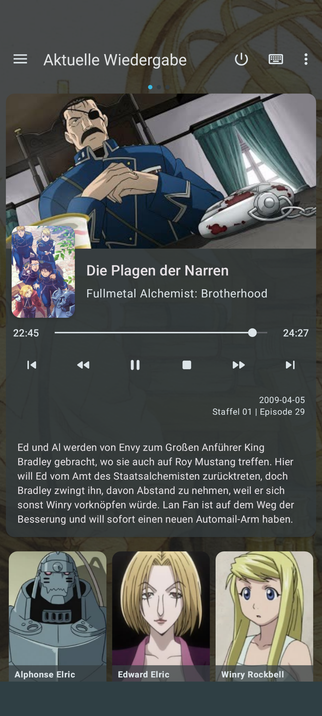 Das Bild zeigt ein Smartphone-Display mit der TV Fernbedienung-App für Kodi namens Kore, die "Die Plagen der Narren" aus "Fullmetal Alchemist: Brotherhood" spielt. Der Titel des Episoden ist "Staffel 01 | Episode 29" und wurde am 5. April 2009 ausgestrahlt. Der aktuelle Abspielzeitpunkt beträgt 22:45 von 24:27. Im Hintergrund ist ein animierter Charakter in einem blauen Militäruniform mit einem Augenpflaster zu sehen. Darunter ist ein Text in deutscher Sprache, der die Handlung des Episoden beschreibt. Die Beschreibung erwähnt, dass Ed und Al von Envy zum Großanführer King Bradley gebracht werden, wo sie auch auf Roy Mustang treffen. Hier will Ed vom Amt des Staatsalchemisten zurücktreten, doch Bradley zwang ihn, davon Abstand zu nehmen, weil er sich sonst Winry vornehmen würde. Lan Fan ist auf dem Weg der Besserung und will sofort einen neuen Automail-Arm haben. Am unteren Bildschirmrand sind drei Charaktere abgebildet: Alphonse Elric, Edward Elric und Winry Rockbell.