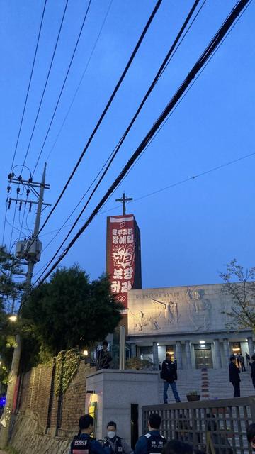 서울 혜화동성당 십자가 첨탑 아래 "천주교는 장애인 탈시설 권리를 보장하라!"는 거대한 현수막이 걸려있다.