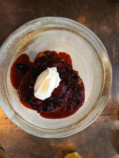 A plate with French toast covered in a fruit compote and whipped cream