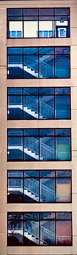 Color image of Superblock Parking Deck staircases, color-coded doors, Akron, Summit County, Ohio, USA, circa 1995. Six levels of staircases seen through full-size windows, each level with a differently colored access door in brown, blue, green, yellow, red, and orange.