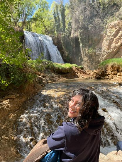 Laura sonriente delante de una enorme cascada.