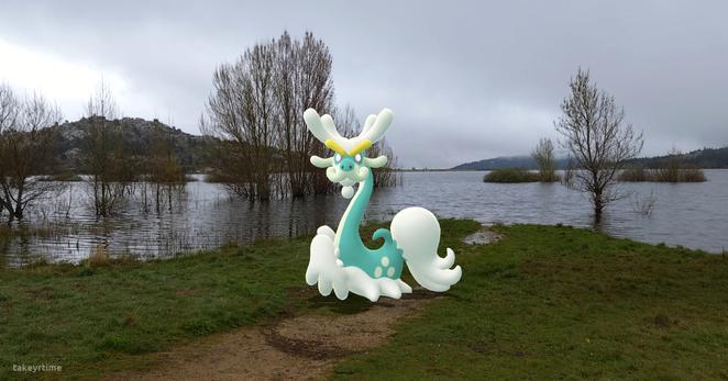 Fotografía realizada con la RA del juego Pokémon GO.
Se ve al pokémon de tipo dragón Drampa con los ojos iluminados y el cuello erguido, mirando fijamente a cámara.
Detrás suya está el Embalse de Navacerrada, se puede ver que hay varios árboles cubiertos de agua. Al fondo, a lo lejos, se ve el muro de la presa del embalse. El cielo está nublado.

Drampa está basado en un dragón chino, es de color turquesa y blanco, sus cejas son amarillas y sus ojos rosados.