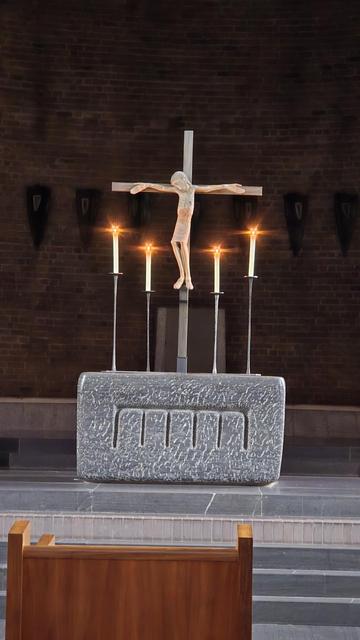 Kreuz auf dem Altar, umrahmt von vier brennenden Kerzen.