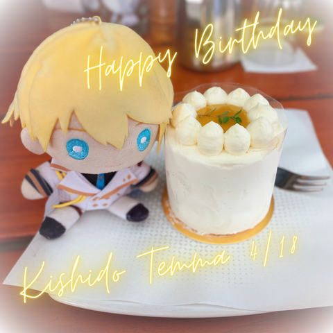 Kishido Temma nui/plushie (blond hair, blue eyes with a white knight unfirom with yellow and black accents) next to a small white cake. The center of the cake is yellow/brown. There's "Happy Birthday Kishido Temma" text.