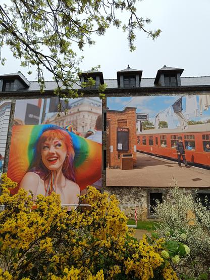Photo géante d'une femme avec un chapeau très coloré sur une façade de maison
