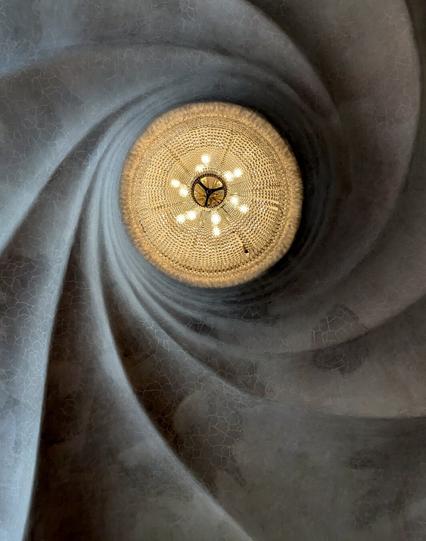 A round chandelier from below, with a twisting relief in the ceiling.