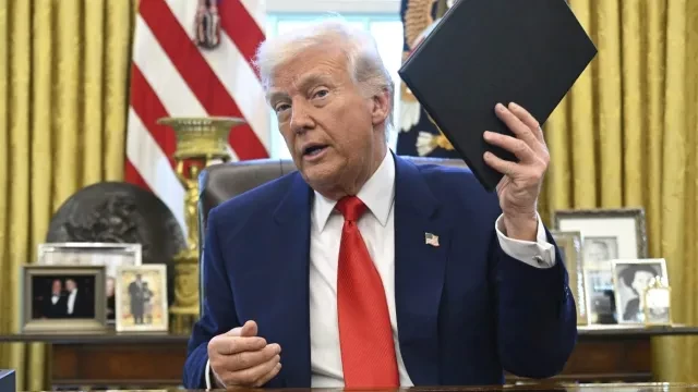 President Donald Trump holds an executive order in the Oval Office of the White House Wednesday, April 9, 2025, in Washington.