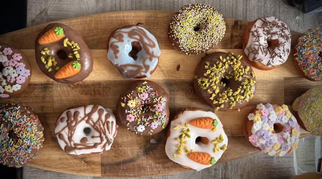 Verschieden dekorierte bunte Donuts auf einem Holzbrett.