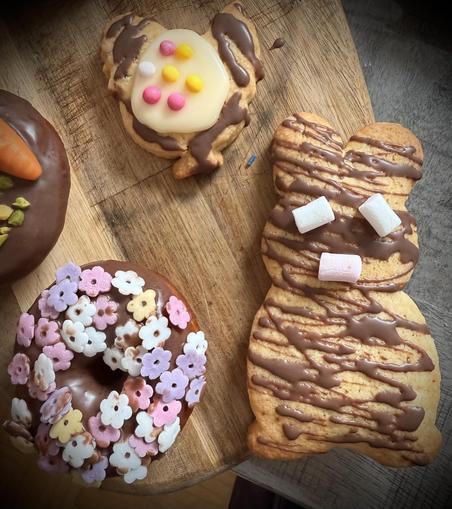 Verschieden dekorierte bunte Plätzchen und Donuts auf einem
Holzbrett
