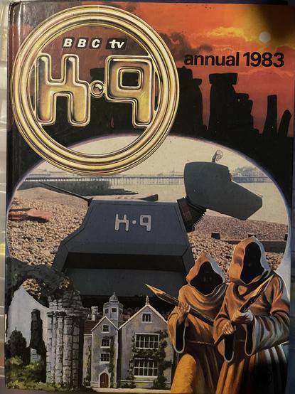 The image features the cover of the 1983 annual for the BBC TV show "K-9." It includes a prominent logo of "K-9" and artistic depictions of a robot dog, a historic building, and two cloaked figures