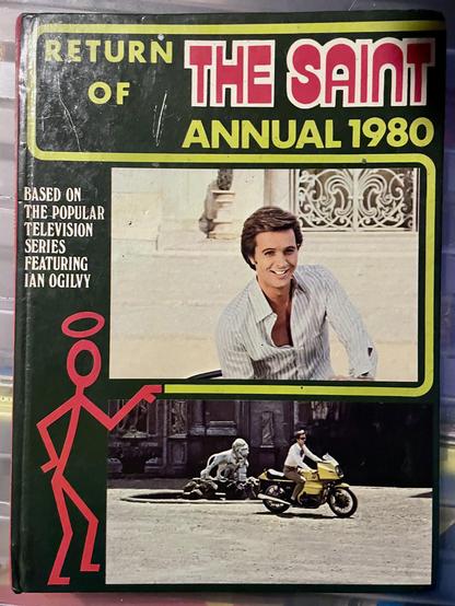 The image features the cover of "Return of The Saint Annual 1980." It includes a photo of a man smiling in a casual shirt, alongside a graphic of a stick figure holding a halo. The bottom section showcases a scene with a man riding a motor bike near a classical statue of lion