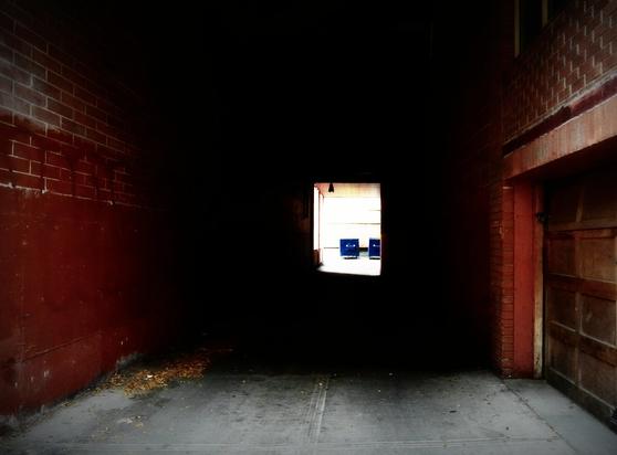 A color photo showing a view of an alley tunnel, looking as it narrows down at the other end.