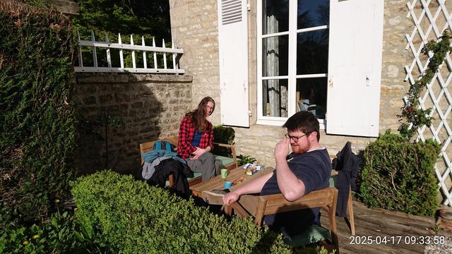 Femme souriante et homme aveuglé par le soleil prenant un café dans une petite cour ensoleillée