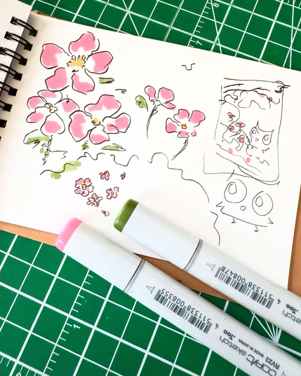 A sketchbook page showing a sketch in pen and marker of a cartoon owl and flowers inspired by cherry blossoms and wild roses