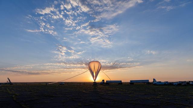 The_Scientific_balloon_eclipses_the_sun_as_it_fills_with_helium,_and_the_High_Altitude_Student_Platform_awaits_launch_(GSFC2024HASP0202).jpg