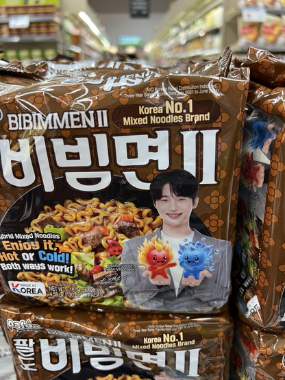Byeon Woo-seok the star of lovely runner kdrama in the cover of bibimen II. These are apparently Korea No 1 mixed noodles brand. The package is brown.  Byeon Woo-seok is holding two cartoons. One is fire creature and the other is ice creature. This may be because you can eat these noodles hot or cold.