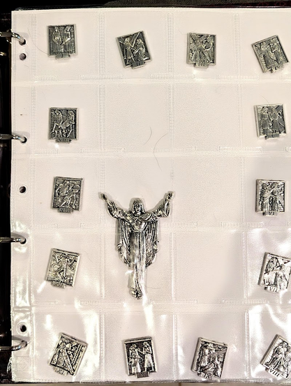 The fourteen stations of the cross pieces around the edge (Clockwise from top-left) and Jesus, arms outstretched as if on the cross in the middle.
