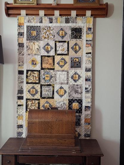 A narrow, long quilt in yellow and cream, featmotifs of butterflies, bees and other garden images