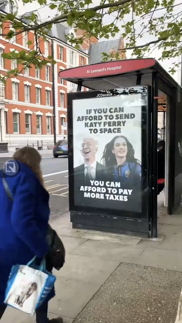 Bus shelter ad in London, with pictures of Bezos and Katy Perry, reading IF YOU CAN AFFORD TO SEND KATY PERRY TO SPACE YOU CAN AFFORD TO PAY MORE TAXES