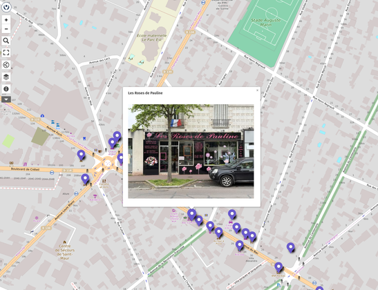 Copie d'écran montrant un fond de carte OpenStreetMap et une série de marqueurs dont l'un affiche la photo d'un commerce de fleurs.