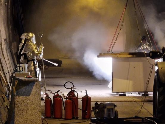 Three people standing around a magnesium fire. While it has the appearance of a satanic ritual, it is in fact a rigorous scientific experiment to test the fire retardant properties of new tunnel cladding materials.