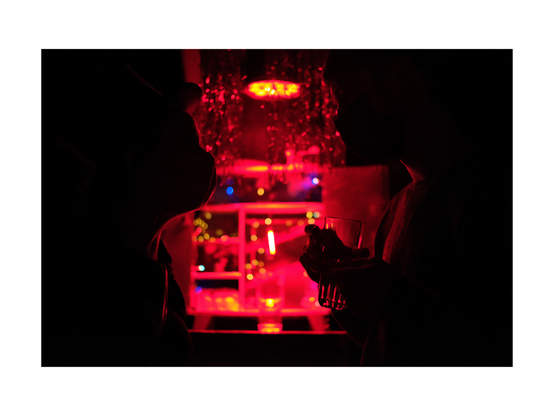 red lighted box with tiny toys and dishes arranged in playful manner as a shrine in low key club situation