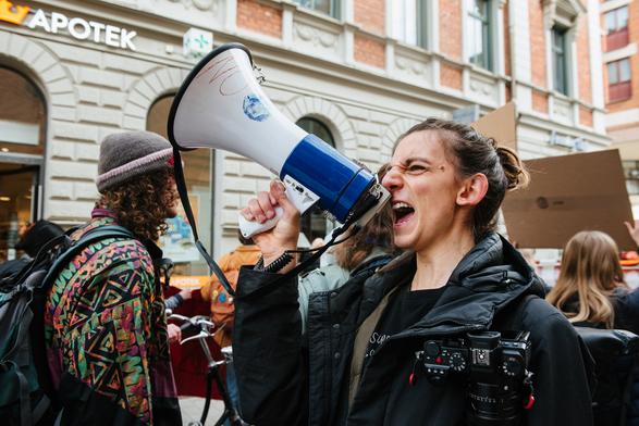 A protester raising slogans on the megaphone while walking backwards in the middle of the march.
