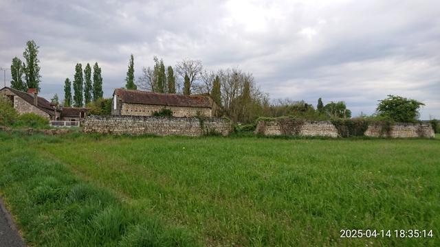 Chouette ferme ancienne tout en pierres entre prés et cyprés, sous un ciel lourd de nuages