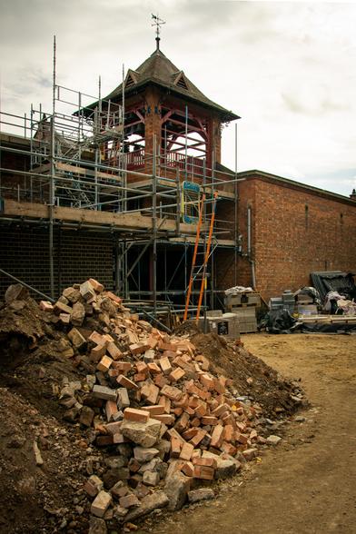 Building work on the Bellfoundry exterior.  Scaffolding in front of the tower. In the foreground is a pile of bricks and rubble.