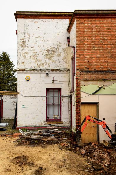 The exterior undergoing building work.  Part of a small digger is visible.