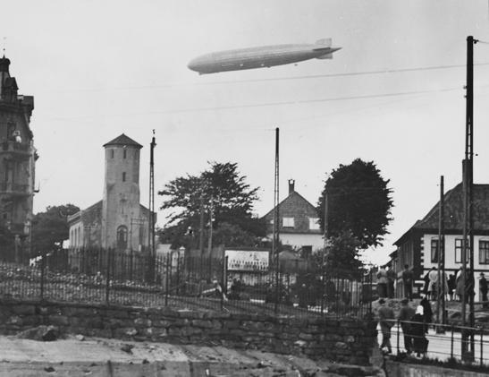 A black and white photo of an airship over Corps de Garde, a fire watch tower at Nordnes in Bergen.