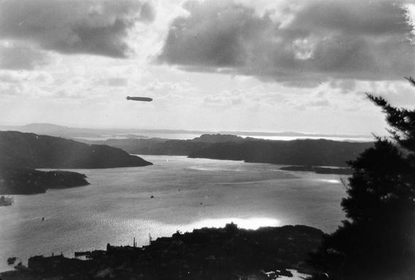 A black and white photo of an airship over Bergen, seen from Mount Fløyen.