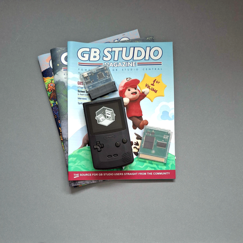 Picture showing GB Studio Magazine, a FPGBC aftermarket Game Boy Color, a 4mb flashcartridge and a GBxCart writing device.