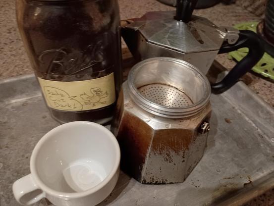 espresso maker on countertop, mason jar of ground coffee, espresso cup.