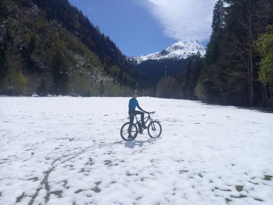 Un ado à vélo dans une prairie enneigée, paysage de montagne