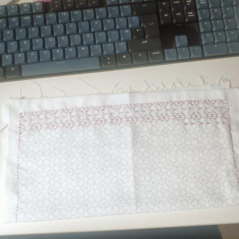 border and first lines done of a sashiko embroidery piece. white cloth, pink thread, sakura pattern.