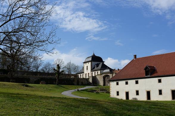Klostergebäude, Turm, grüne Wiese und blauer Himmel im April