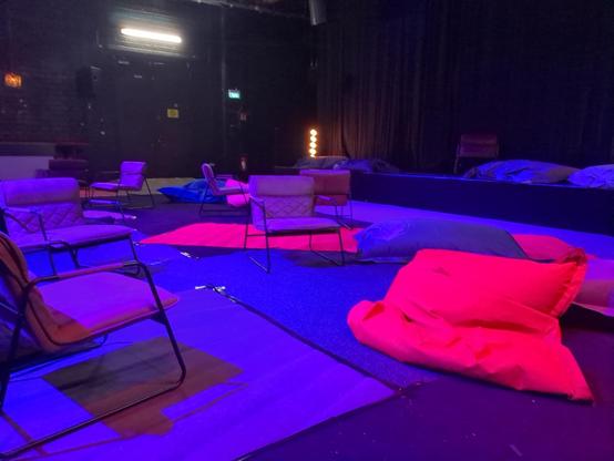 Snapshot of "comfy cuddly quiet hackcenter". Cushioned chairs and bean bags are visible, the light is dimmed, everything looks blue, purple and pink.