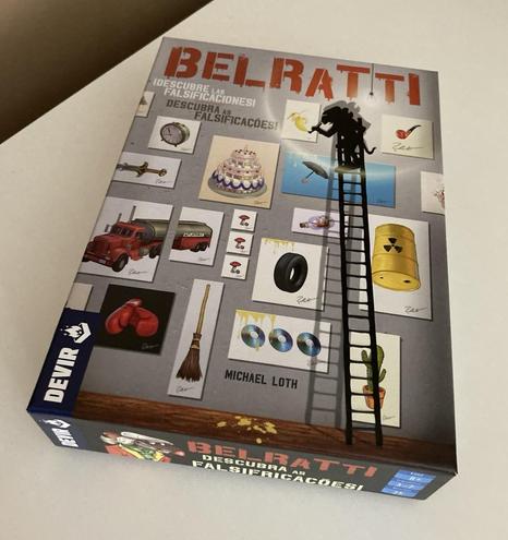 Caixa do jogo Belratti da editora Devir. Uma figura sombria no alto de uma escada de mão pinta quadros representando objetos diferentes, como um relógio, banana, caminhão.
