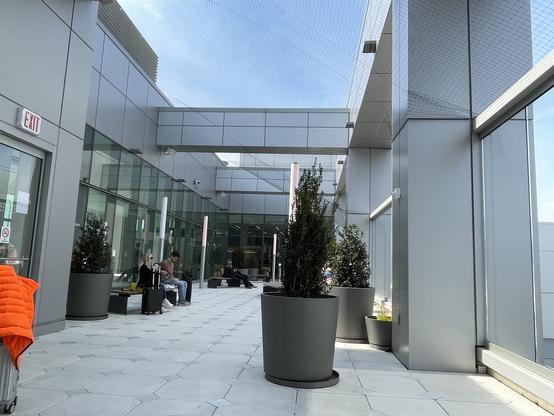 View along the outdoor terrace with benches and potted shrubs