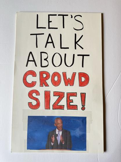 A protest sign has an image of Obama making his viral crowd size hand gesture and says “Let’s Talk About Crowd Size!”