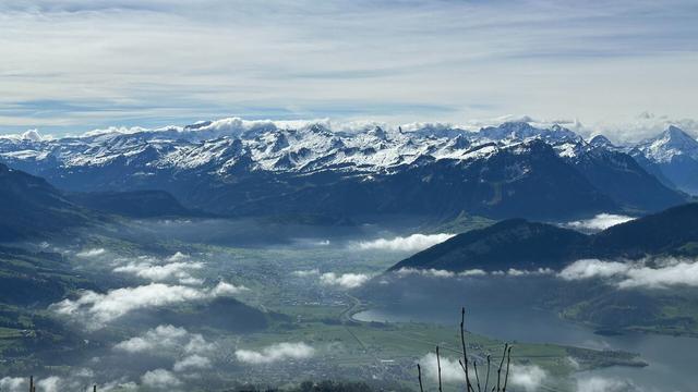 View of distant snow-covered Swiss Alps. The valley in the foreground has drifting low-lying clouds.