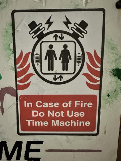 A sticker in the style of an safety warning notice showing the standard image of two people on a lift surrounded by a black circle with electric sparky things on top. Red flames lick in from both sides. Below, white text on a red background reads “In case of fire do not use Time Machine”.