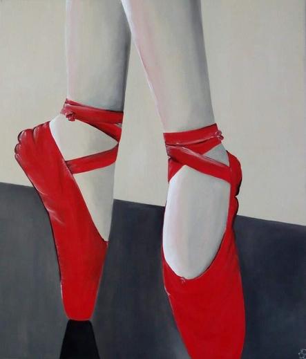 Voeten in rode balletschoenen op een donkergrijze vloer. Ze staat op haar tenen in spitzen.