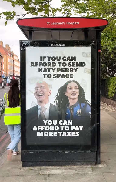Plakat przedstawiający Katy Perry i szefa Amazon Jeffa Bezosa i napis:

Jeśli stać cię na wysłanie w kosmos Katy Perry,
to stać cię na płacenie wyższych podatków