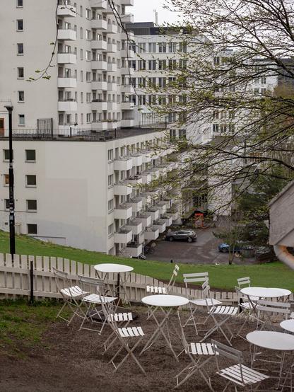 White café furniture, with a large white office and apartment building in the background