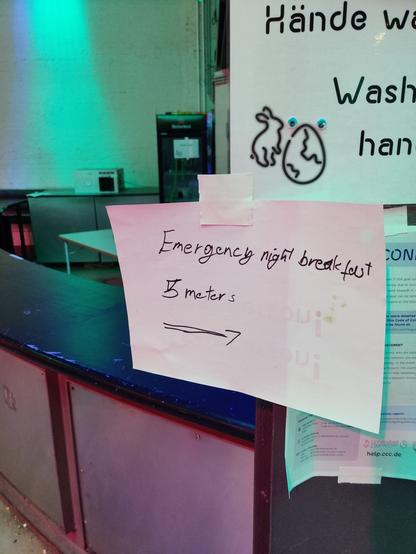 Sign saying "Emergency night breakfast, 5 meters" with an arrow pointing right. In the background is the "eternal" breakfast.