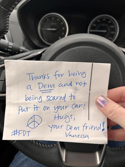 A handwritten note in blue pen that reads “thanks for being a Dem and not being scared to put it on your car! Hugs, your Dem friend Vanessa. #FDT”