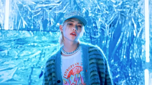 Felix in a room covered with crinkled foil. He's wearing a jewelled tiara over a pale blue baseball cap, a fuzzy blue striped cardigan, and a t-shirt with EUROPEAN TOUR 1979 AC/DC on it