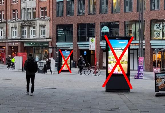 Eine Fußgängerzone. Man geht direkt auf 2 Werbebildschirme zu, einem in der Bushaltestelle integrierten und einem freistehenden, die synchron das gleiche Bild zeigen.